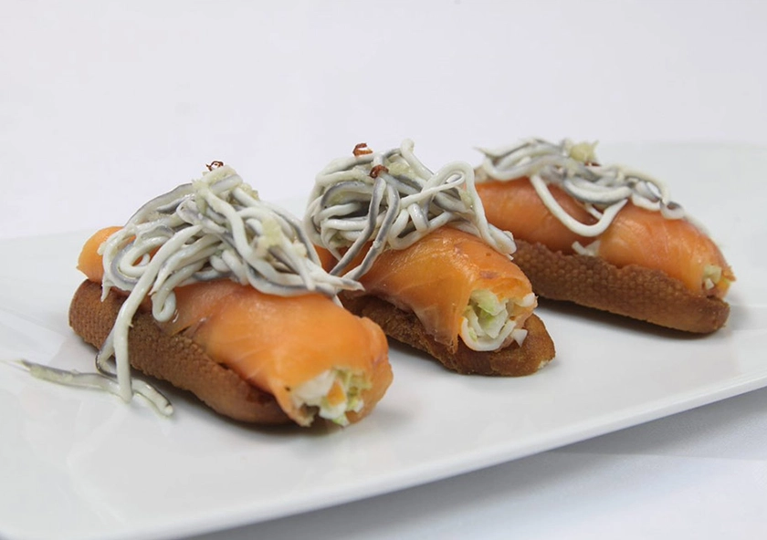 Rollitos de salmón y anguriñas sobre pan frito